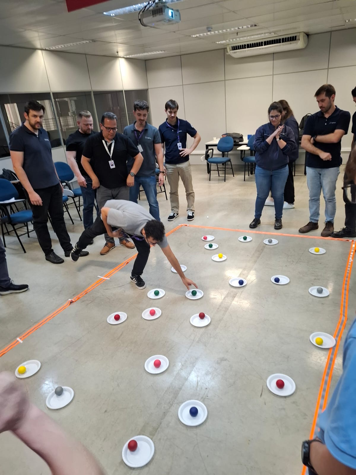 Participantes em dinâmica de equipe com desafio no chão
