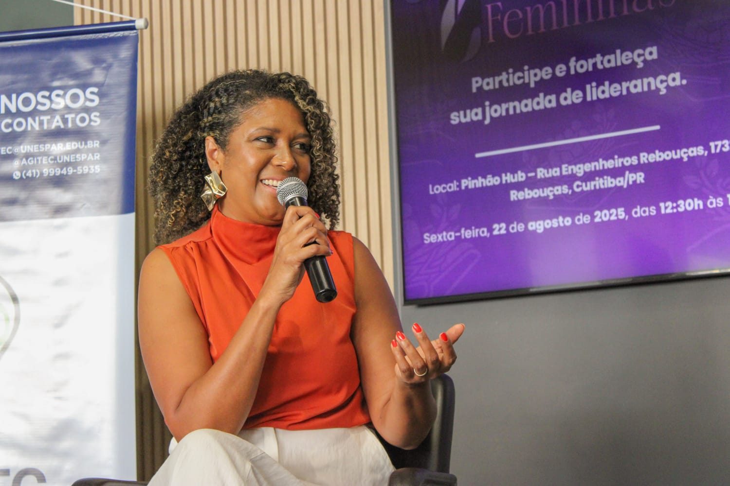 Cintya Santos com microfone durante palestra corporativa